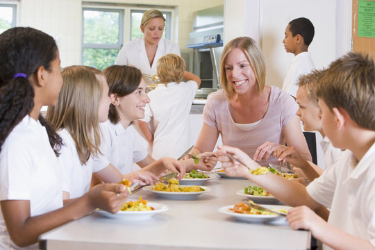Teacher and schoolchildren enjoying their lunch in a school cafe