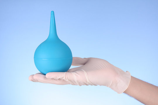 Small enema on hand with blue background