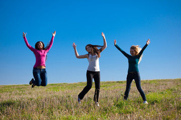 Fototapeta na wymiar three young beautiful woman jumping into the field against the s