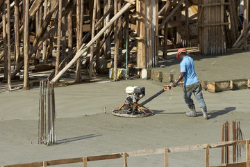 Bauarbeiter glättet den frischen Beton mit einem Flügelglätter