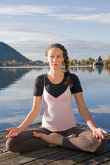 Fototapeta premium Junge Frau beim Yoga am See