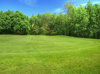 Vibrant image of golf course with flag and fairway in sun
