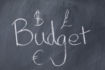 Word "budget" and currencies on a blackboard
