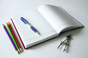An open book with a pencil and a pen on a white background