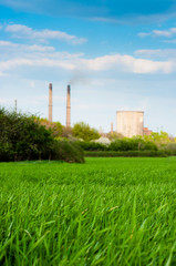 Fototapeta na wymiar Fresh green grass with nuclear power plant and blue sky