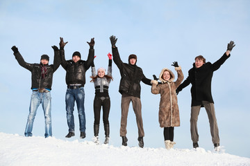 Young people jump in winter on snow and lift hands upwards