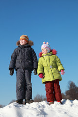 girl in jacket and boy standing at snow outdoors at winter