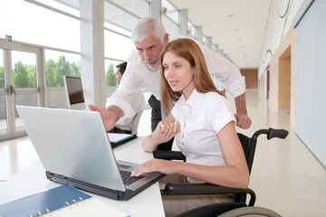 Woman in wheelchair with trainer in office