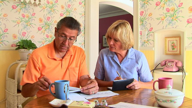 Mature Couple Going Over Bills At Table