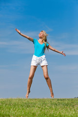 Fototapeta premium The happy young woman jumps in the field