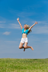 The happy young woman jumps in the field