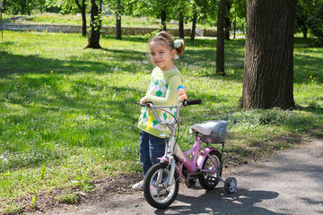Fototapeta na wymiar little girl with bicycle posing in park