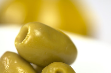 Closeup of a green olive with olive oil in the back