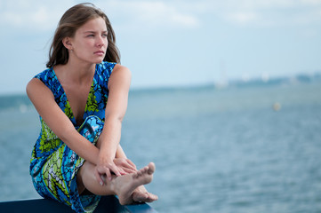 Fototapeta na wymiar sad woman sitting over sea at summer day