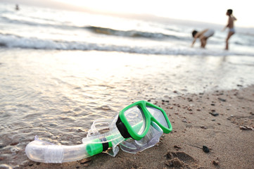 Snorkeling mask on the beach, children playing around