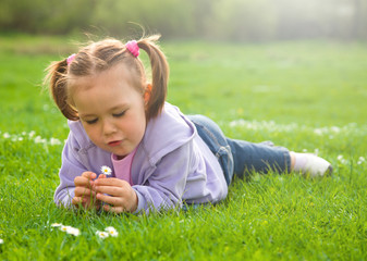 Little girl is laying on green meadow