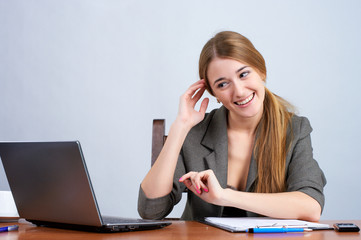 Happy young businesswoman working on laptop