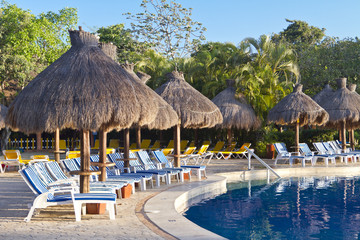 Naklejka na ściany i meble Sunloungers beside a tropical swimming pool