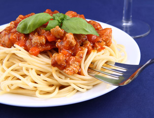 Spaghetti bolognese on a plate being eaten with a fork