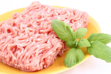 Raw minced meat on a plate decorated with basil
