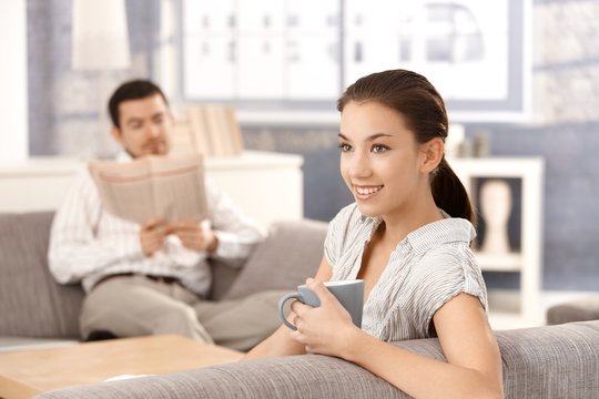 Young couple sitting on sofa at home smiling