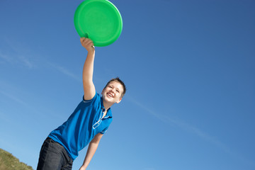 Boy playing frisbee on beach - obrazy, fototapety, plakaty
