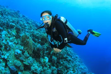 Rolgordijnen Jonge vrouw duiken over koraalrif © Richard Carey