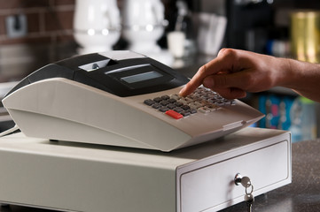 Closeup of a cashier's hand ringing cash register. - obrazy, fototapety, plakaty