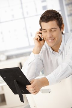 Businessman on phone looking at photo frame