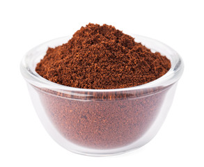 Natural ground coffee heap in transparent glass bowl, isolated o