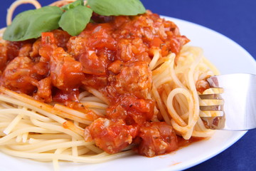 Spaghetti bolognese on a plate being eaten with a fork
