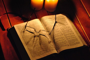 Student studying Holy Bible by Candlelight