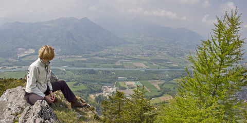Naklejka premium frau sitzt auf gipfel in oberbayern und schaut ins inntal