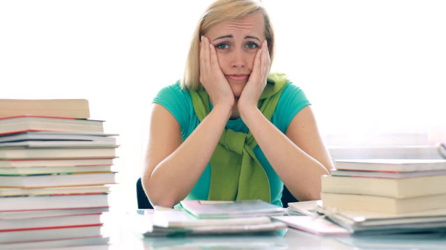 Worried unhappy female student with to much books