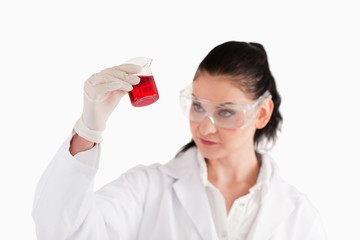 Isolated scientist looking at a red beaker