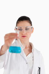 Female scientist wearing safety glasses and holding a blue flask