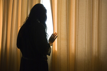 depressed woman by window - obrazy, fototapety, plakaty