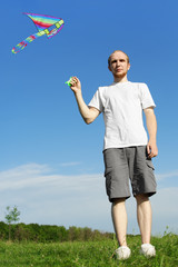 man in white shirt standing on summer meadow and flying kite, fu