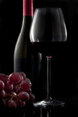 Fototapeta premium Glass of red wine with bottle and grapes