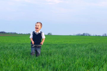 Naklejka na ściany i meble A beautiful little boy staing in the grass