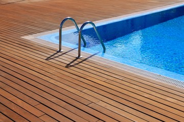 blue swimming pool with teak wood flooring - obrazy, fototapety, plakaty