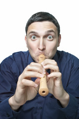 Funny young man trying to play block flute isolated on white © liubomirt