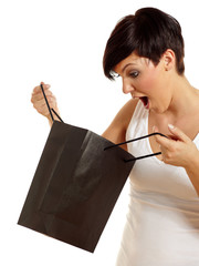 Surprised young woman looking in a black shopping bag