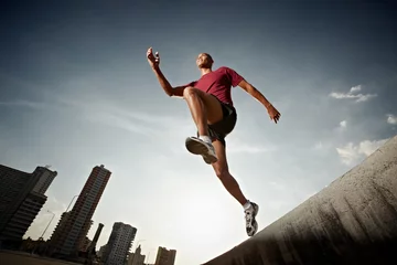Papier Peint photo Jogging hispanic man running and jumping from a wall