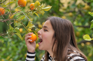 Girl eating an orange from the tree - 32212130