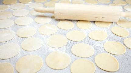 round shape of the dough and rolling pin with flour on the table