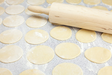 round shape of the dough and rolling pin with flour on the table