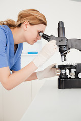 Blond-haired scientist looking through a microscope