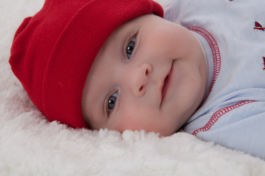 Adorable baby boy lying smiling with red hat on