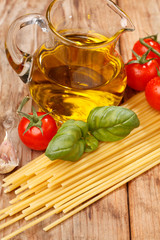 pasta, olive oil and tomatoes on the wood background